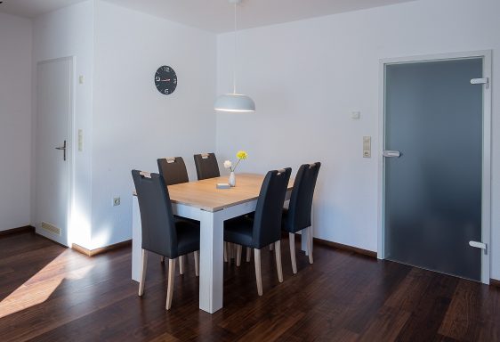 Essbereich Esszimmer mit einem Holztisch und sechs schwarzen Stühlen, hell und modern eingerichtet.