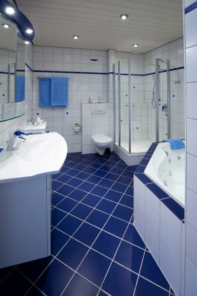 Bad Modernes Badezimmer mit blauen Fliesen, Dusche, Waschbecken und Toilette.
