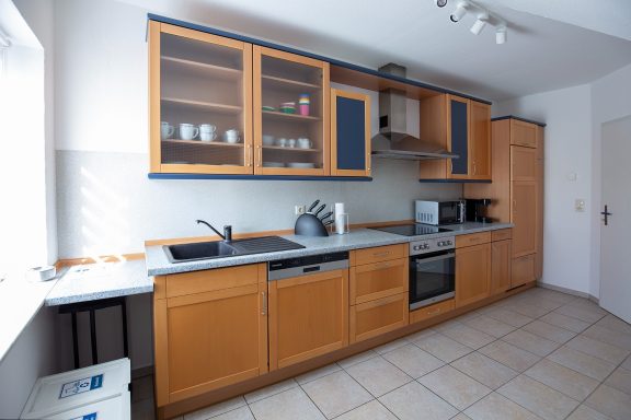 Küche Moderne Küche mit Holzschränken, Edelstahlgeräten und Fliesenboden.