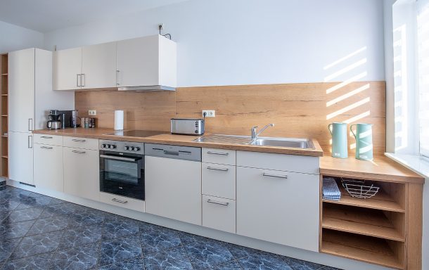 Küche Moderne Küche mit Holz- und weißen Elementen, ausgestattet mit Herd, Kühlschrank und Ablagen.