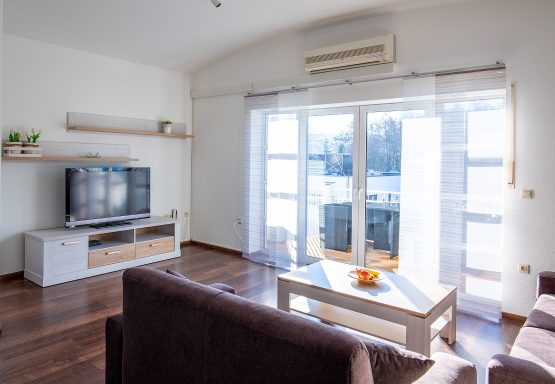 Wohnbereich Helles Wohnzimmer mit Fernseher, Sofa und Balkonzugang.